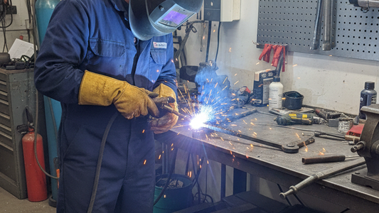 a man welding the broken metal boot scrapper in the work shop