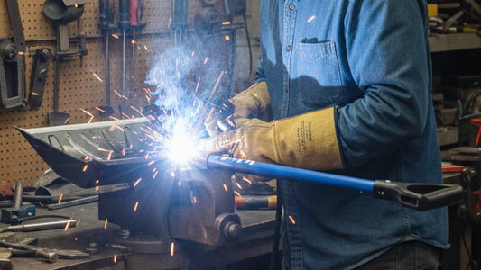 a man welding the shovel's leading edge in the workshop to fix the fracture