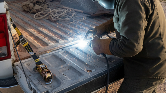 a man welding the truck bed tie-downs on the truck bed
